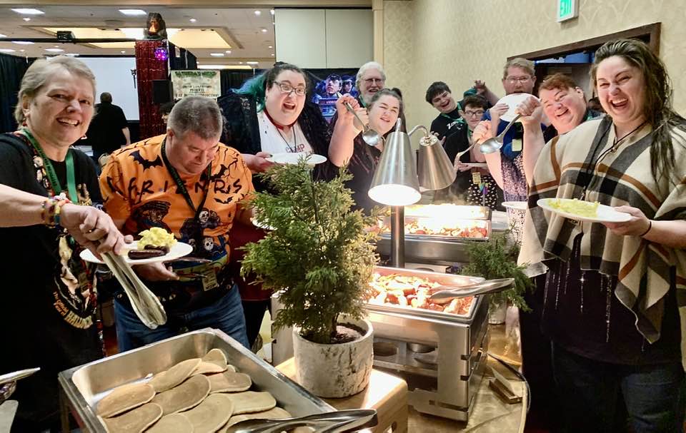 A group of people eating food at a convention.