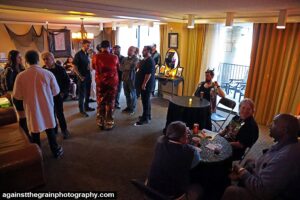 A group of people in a dimly-lit room, some in costumes, socializing and seated at tables, enjoyed an exclusive atmosphere reminiscent of a Celebrity Meet and Greet for Platinum ticket holders only.