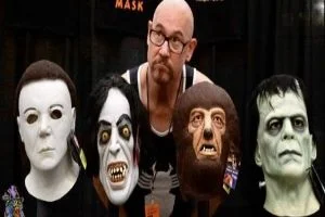 A man is posing in front of a group of masks.