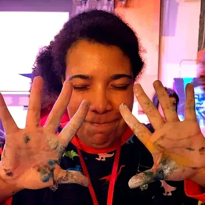 Kcie Monk, a woman with her hands covered in paint.