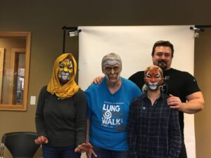 Four Dutch partiers with animal face paint pose together; one wears a yellow scarf, another a "Lung Walk" shirt.