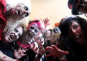 Group of people in zombie makeup with wild expressions, reaching toward the camera at a Seattle thrillers event.