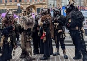 Costumed Krampus Bremerton participants gather outdoors at the festival, pausing for a quick group selfie.