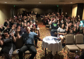 Participants at a film festival with their hands up.