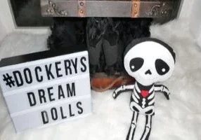 A skeleton sits next to a sign that says docker's dream dolls.